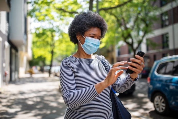 woman in mask looking at her cell phone