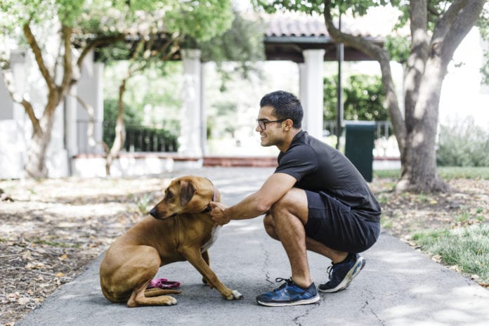 Young Man Embracing Dog By Spanish Patio