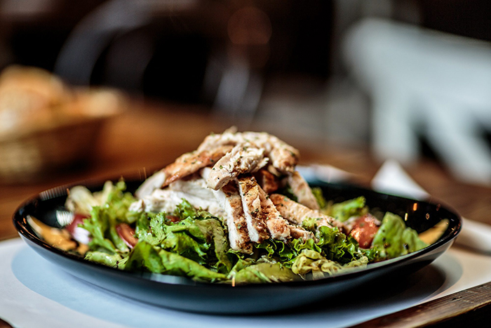 photo of a plated salad with grilled chicken on top