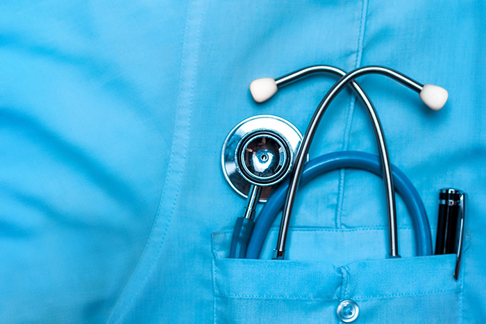 A closeup photo of a doctor's stethoscope in the shirt pocket of their scrubs