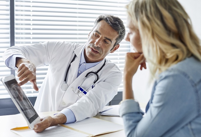 physician using medical tablet to give information to patient