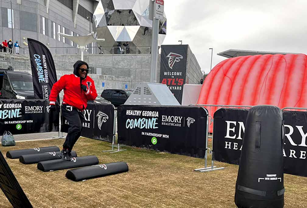 A person completes an obstacle course outside a football stadium.