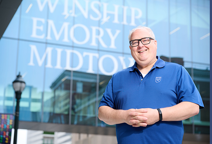 patient wade stands smiling in front of winship cancer institute of emory healthcare in atlanta georgia